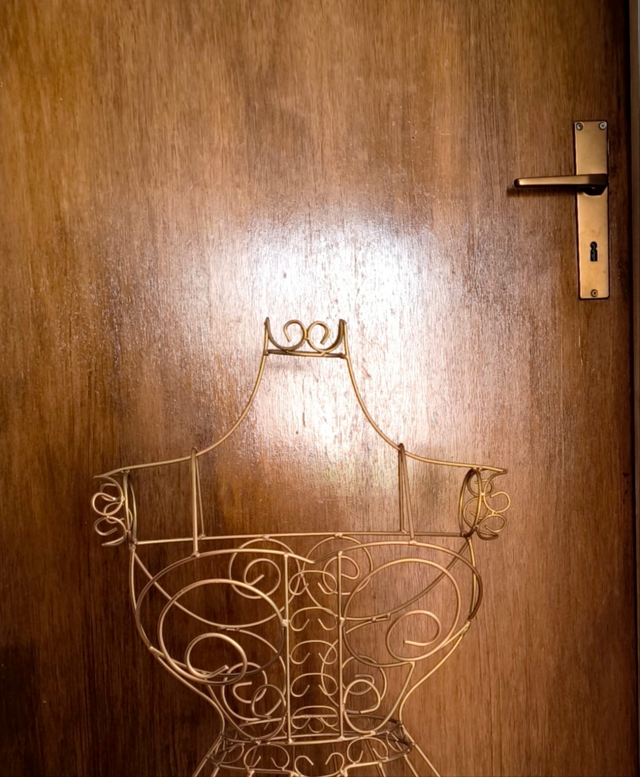 Skulptur im Entstehen – goldfarbene Drahtbüste mit ornamentalen Schwüngen, Atelieraufnahme vor einer Holztür